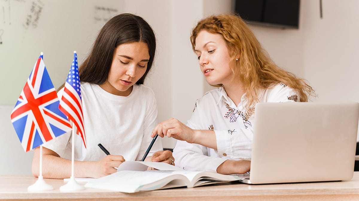 Foreign school private study with a school girl. Teacher explain grammar of native language using laptop. Prepearing to exam with tutor. English and British flags in front.